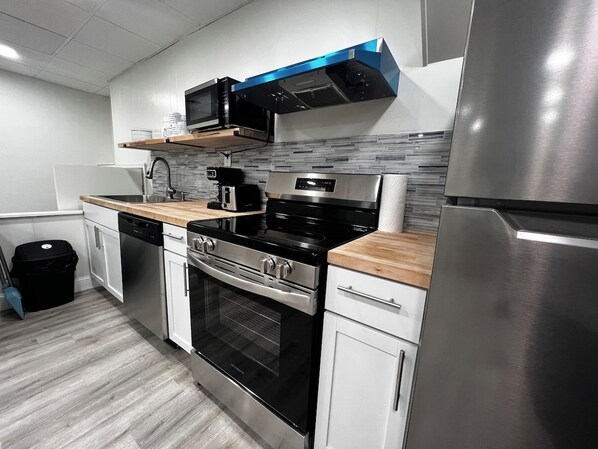 Moderni keittiö, jossa on ruostumattomasta teräksestä valmistetut kodinkoneet, mikroaaltouuni, liesi ja astianpesukone.