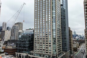 A high-rise building with a grid of windows, surrounded by other tall buildings and a busy street. - Refined 1BR Suite-Workspace & Fast Wi-Fi (Toronto)