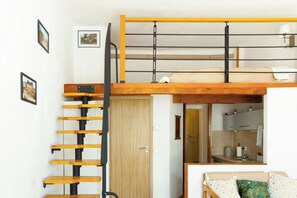 A room with a bunk bed, a wooden ladder, a door, and a kitchenette. - Krakow Old Town Within Easy Reach - Kazimierz Apartment (Kraków)