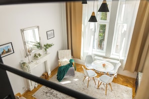 A room with a dining table, chairs, a fireplace, a mirror, and a window with curtains. - Krakow Old Town Within Easy Reach - Kazimierz Apartment (Kraków)