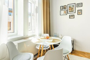 Ein stilvoller Essbereich mit einem runden Tisch, weißen Stühlen und Blick auf die Stadt durch große Fenster.