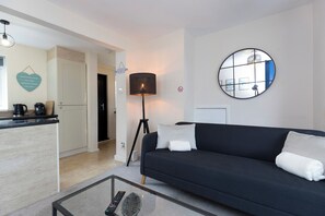 Un salon moderne avec un canapé foncé, une table basse, une lampe et un miroir rond accroché au mur.