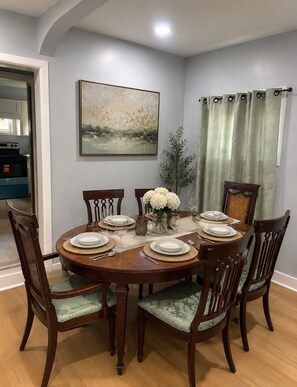 A dining room with a round table set for six, surrounded by wooden chairs with cushioned seats. - Casa Bellavista | Walk to Falls | Skyline Views (Niagara Falls)