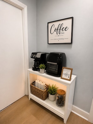A coffee bar setup with a coffee machine, a sign that reads 'Coffee Bar love is brewing,' and a framed sign that says 'But first, coffee.' - Casa Bellavista | Walk to Falls | Skyline Views (Niagara Falls)