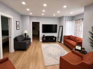 A living room with a flat-screen TV, two sofas, a coffee table, and a rug. - Casa Bellavista | Walk to Falls | Skyline Views (Niagara Falls)