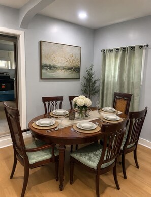 A dining room with a round table set for six, surrounded by six chairs with cushioned seats. - Whole 621 Home - Sleeps 16 - Walk to Falls (Niagara Falls)