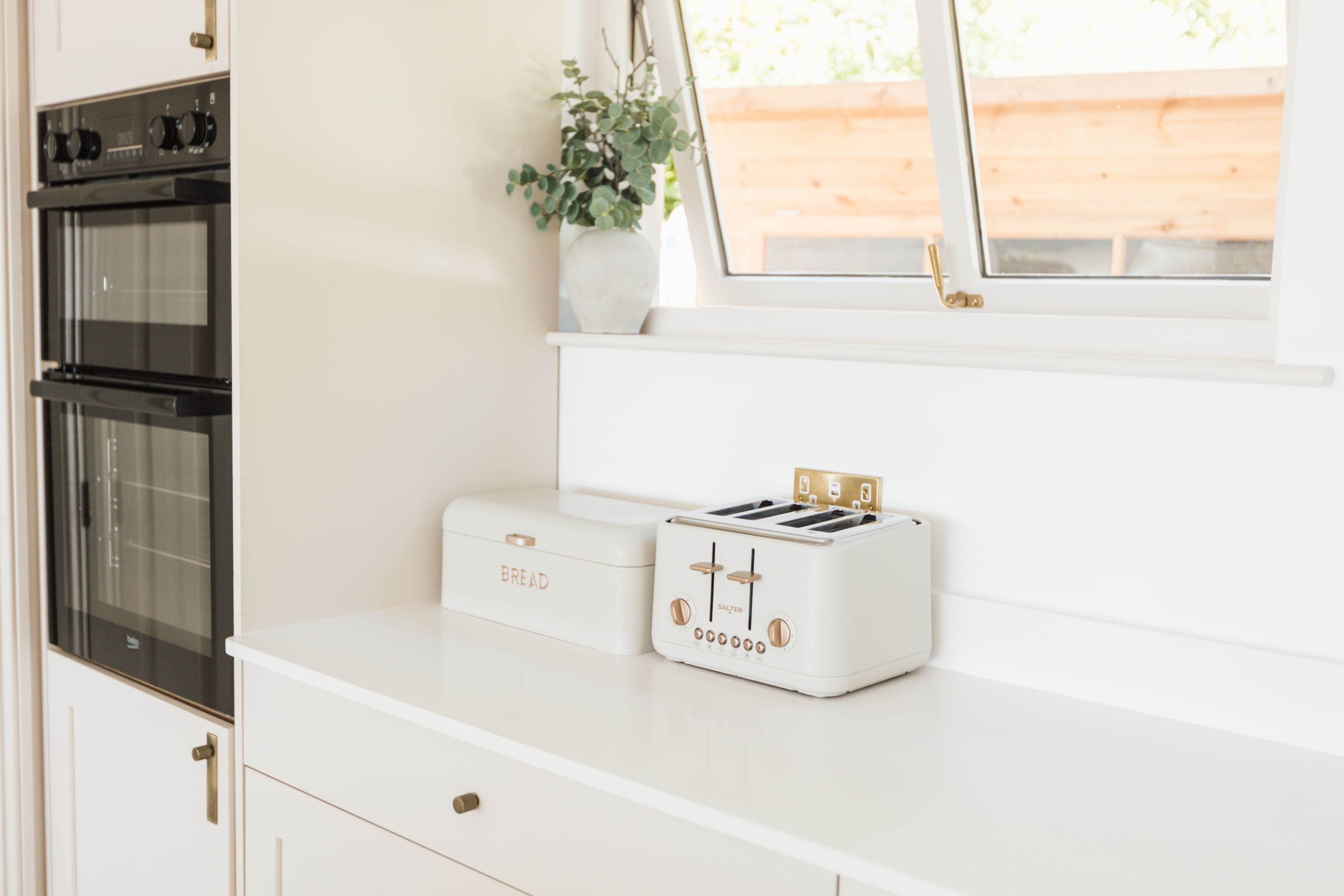 A kitchen with a white countertop, a toaster, and a bread box.