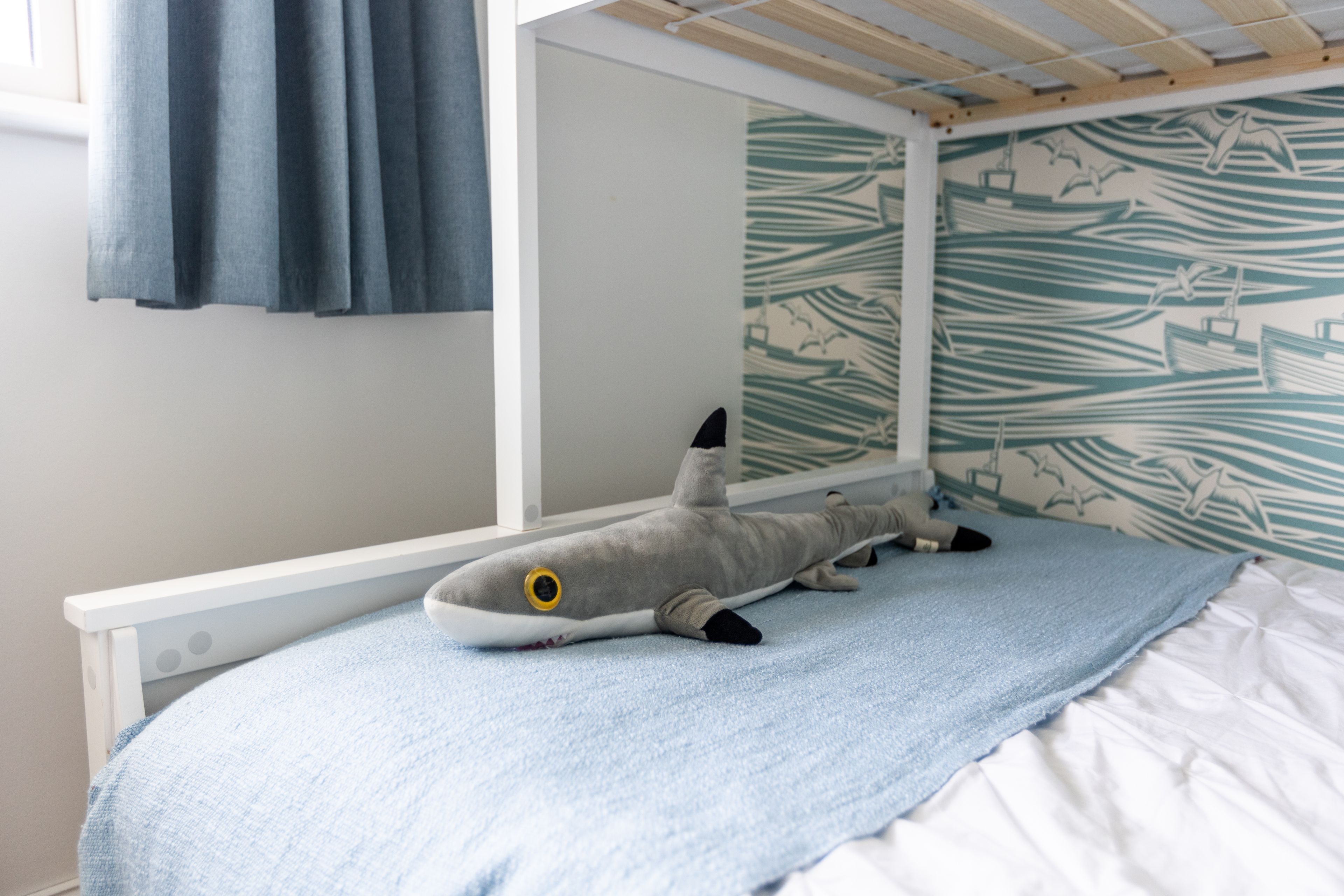 A bunk bed with a plush shark toy on the lower bunk.
