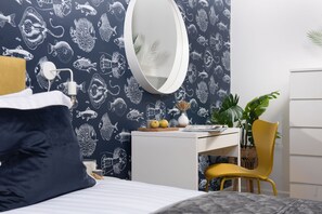 Ein Schlafzimmer mit einem Bett, einem Schreibtisch, einem Stuhl, einem Spiegel und einer Wand mit Fischmuster.