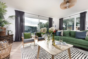 A modern living room with a green sofa, two armchairs, a coffee table, and a large window with curtains. - Meadow Retreat - Sleeps 12 | 4 Bedrooms | Hot Tub | Sauna | Cinema Room | Games Room | Dog Friendly (Hatt, Saltash, Cornwall)