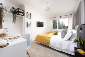 A modern bedroom with a bed, a desk, a chair, and a window. - Meadow Retreat - Sleeps 12 | 4 Bedrooms | Hot Tub | Sauna | Cinema Room | Games Room | Dog Friendly (Hatt, Saltash, Cornwall)
