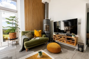 Una sala moderna con sofá, televisión, chimenea y vistas al exterior.