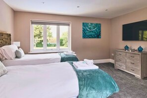 A hotel room with two beds, a large window, a flat-screen TV, and a painting on the wall. - Heronbrook Retreat, Bedfordshire | Outdoor Pool, Hot Tub, Sleeps 20 (Bedford)