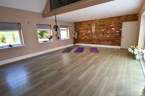 A spacious room with a wooden floor, a brick wall, and a door. - Heronbrook Retreat, Bedfordshire | Outdoor Pool, Hot Tub, Sleeps 20 (Bedford)