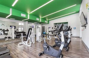 A gym with exercise equipment, mirrors, and green lighting. - Cozy 1-bedroom condo in Downtown Atlanta with fitness room and pool (Atlanta)