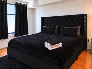 A modern bedroom with a large bed, black headboard, and a black rug. - Cozy 1-bedroom condo in Downtown Atlanta with fitness room and pool (Atlanta)