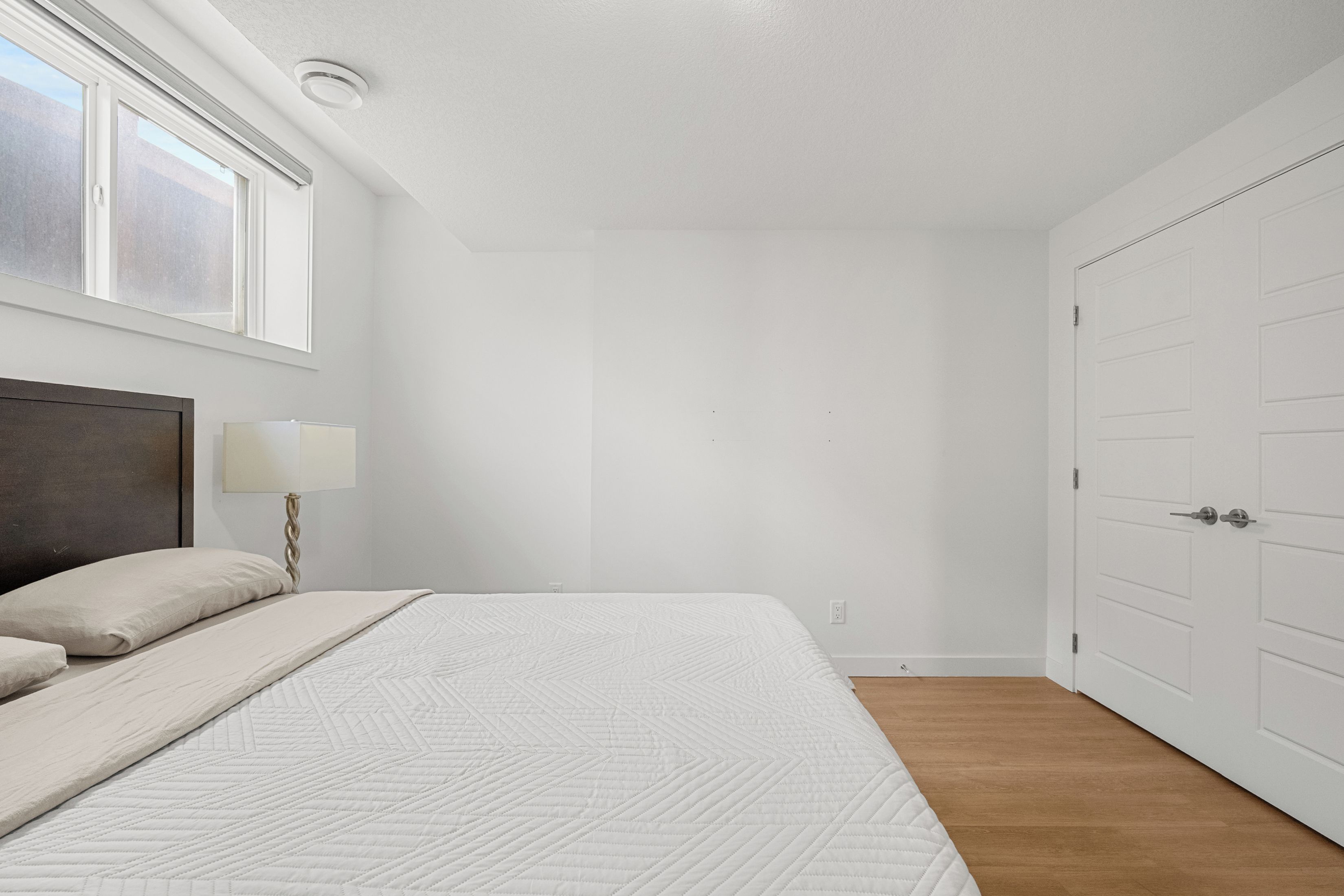 A bedroom with a bed, a nightstand, a lamp, and a wardrobe.