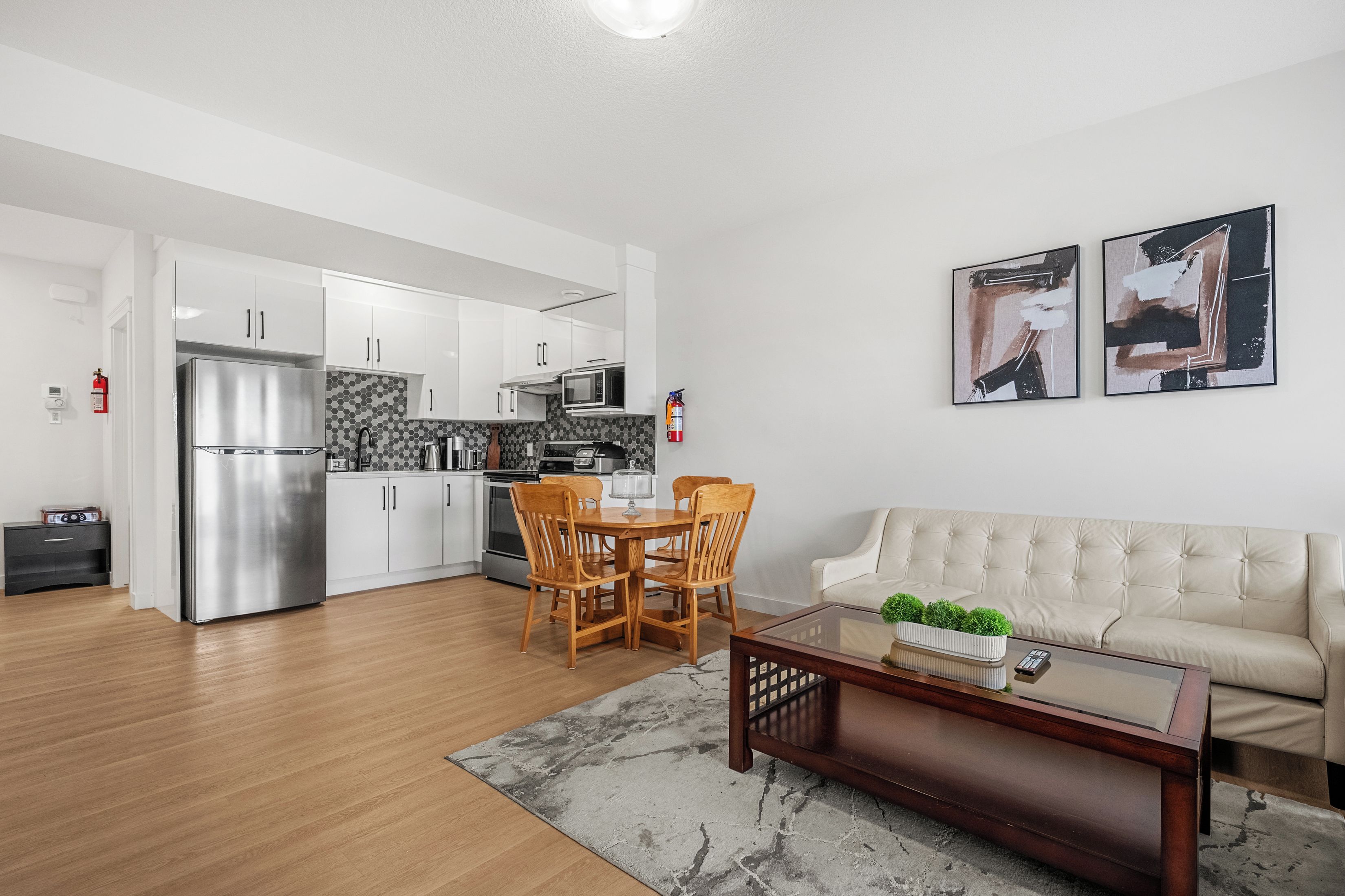 A modern kitchen with white cabinets, a stainless steel refrigerator, and a microwave.