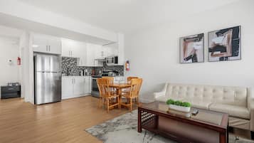 A modern kitchen with white cabinets, a stainless steel refrigerator, and a microwave.