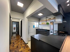 A modern kitchen with a central island, built-in appliances, and a herringbone wood floor. - Apartment one block from the beach, central location, close to many attractions. (Balneário Camboriú)