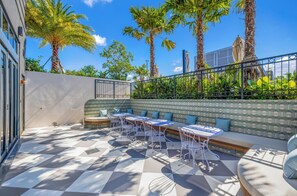 An outdoor seating area with tables and chairs, surrounded by palm trees and a patterned wall. - NoMad Wynwood Studio Suite with Balcony & Rooftop Pool (Miami)