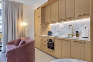 A modern kitchen with wooden cabinets, a marble countertop, and a Bosch oven. - NoMad Wynwood Studio Suite with Balcony & Rooftop Pool (Miami)