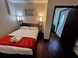Een hotelkamer met een bed, twee bedlampen, een deur met een ruit en een wand met een bloemwerk.