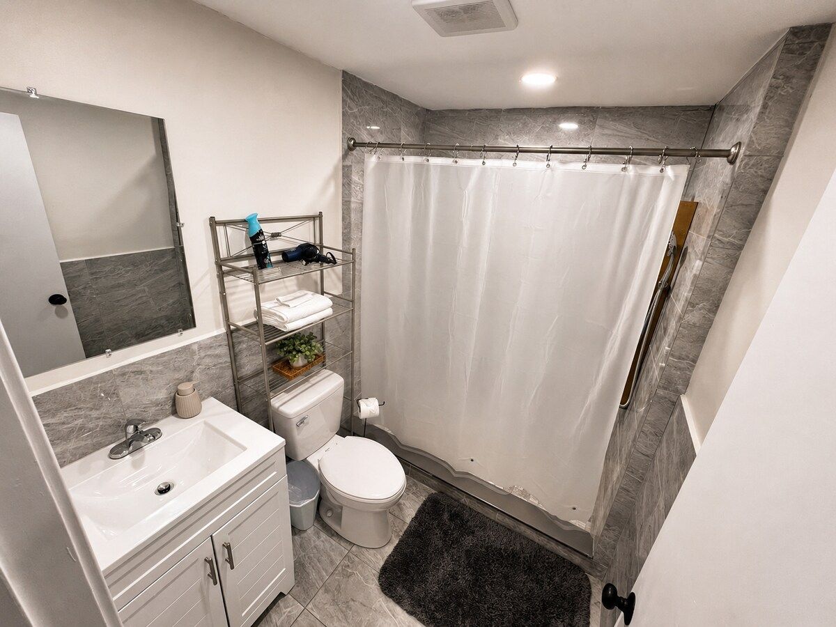 Un baño moderno con cortina de ducha, inodoro, lavabo y espejo.