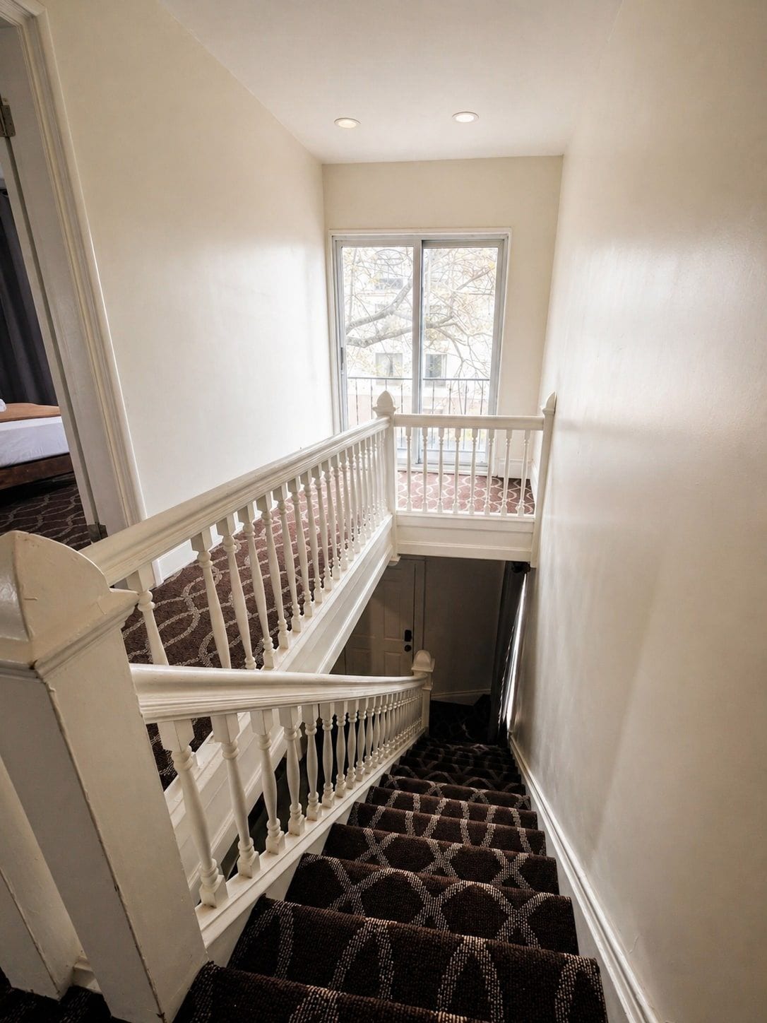 A staircase with white balusters leading to a landing with a window.
