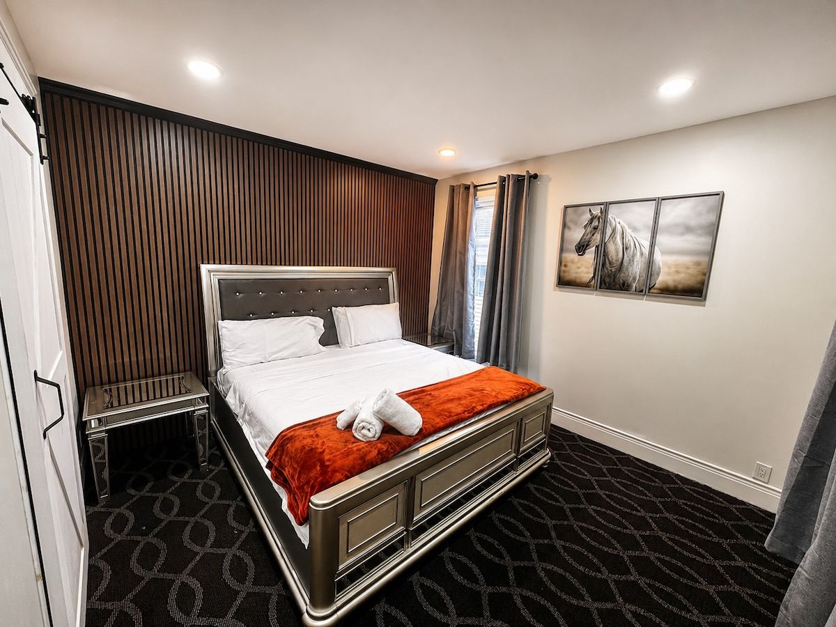 A hotel room with a bed, bedside table, and a painting on the wall.