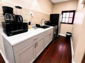 A kitchen with a microwave, coffee maker, and blender on the counter, a sink, and a refrigerator. - Cozy 2BR 1 Block to Falls Perfect Couple Getaway (Niagara Falls)