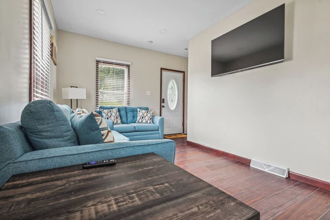 A living room with a sofa, a coffee table, and a television mounted on the wall.