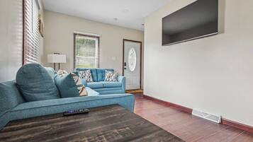 A living room with a sofa, a coffee table, and a television mounted on the wall.