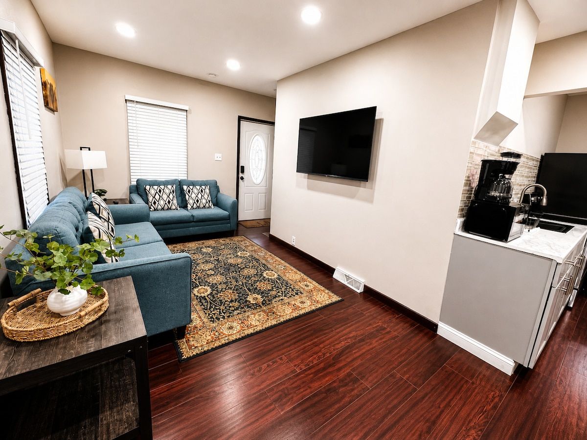 A modern living room with a sofa, a coffee machine, and a flat-screen TV.