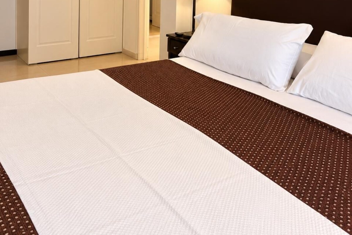 Una habitación de hotel con una cama grande, una mesita de noche, una lámpara y un armario.