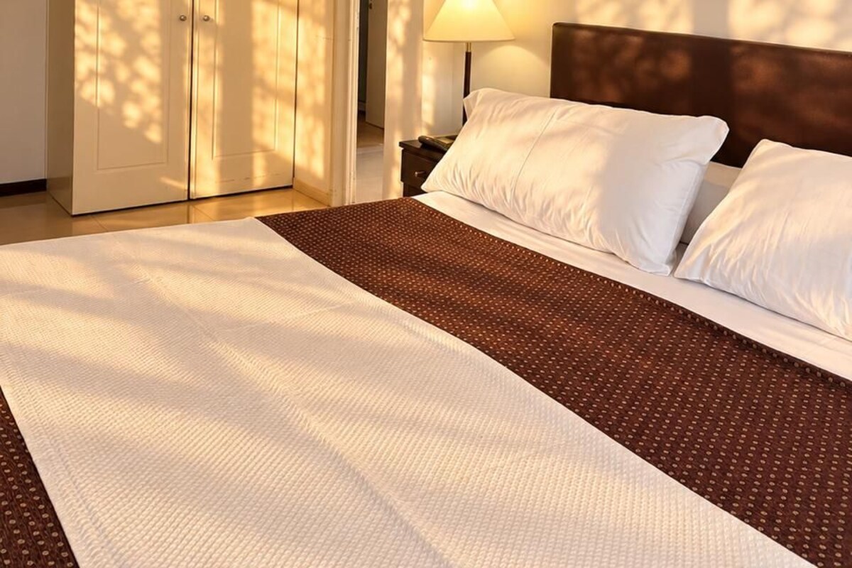 Habitación de hotel con una cama grande, una mesita de noche, una lámpara y un armario.