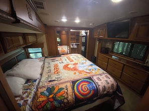 Une chambre à coucher avec un grand lit, une télévision et une armoire.