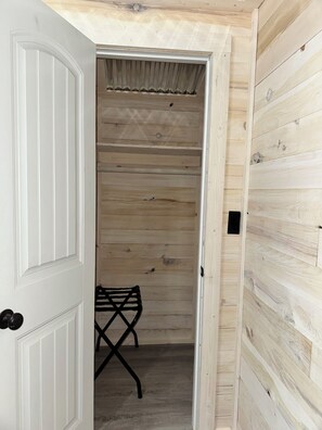 A wooden interior with a white door, a black metal chair, and a wooden wall. - Quaint Tiny Home with Kitchen (Columbia)
