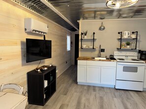 A modern kitchen with white cabinets, a built-in stove, and a wooden countertop. - Quaint Tiny Home with Kitchen (Columbia)