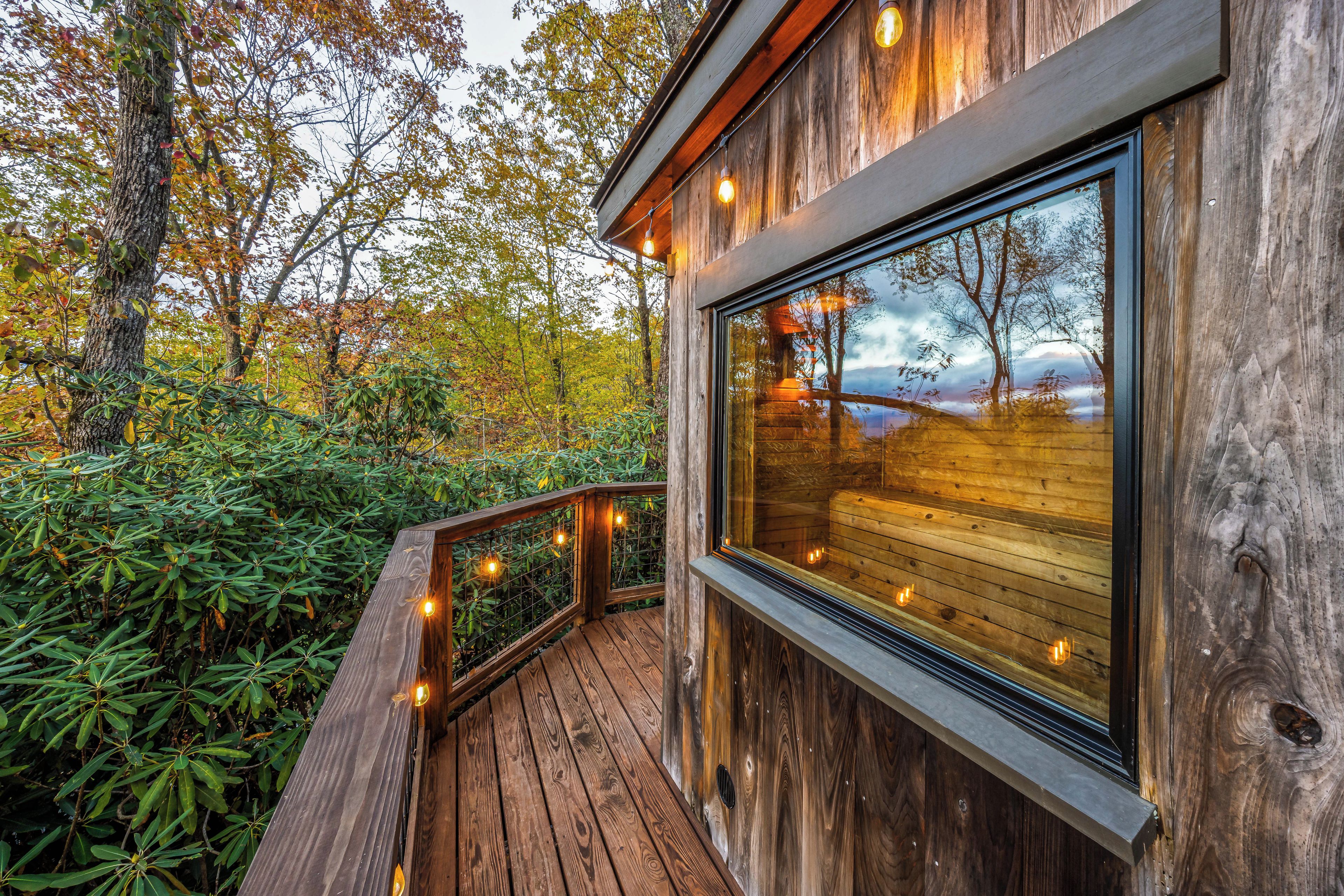 A wooden deck with a railing, surrounded by trees and foliage.
