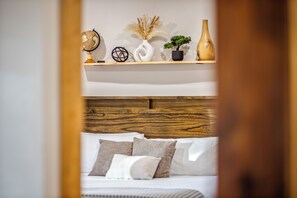 A bedroom with a wooden headboard, a bed with white bedding, and a shelf with decorative items including a globe, a vase, and a plant. - Majestic Mountain View, Hot Tub, Outdoor Shower, Sauna & Game Room (Penrose)