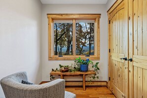 A room with a wooden window, a wooden door, a chair, and a small table with plants. - Majestic Mountain View, Hot Tub, Outdoor Shower, Sauna & Game Room (Penrose)