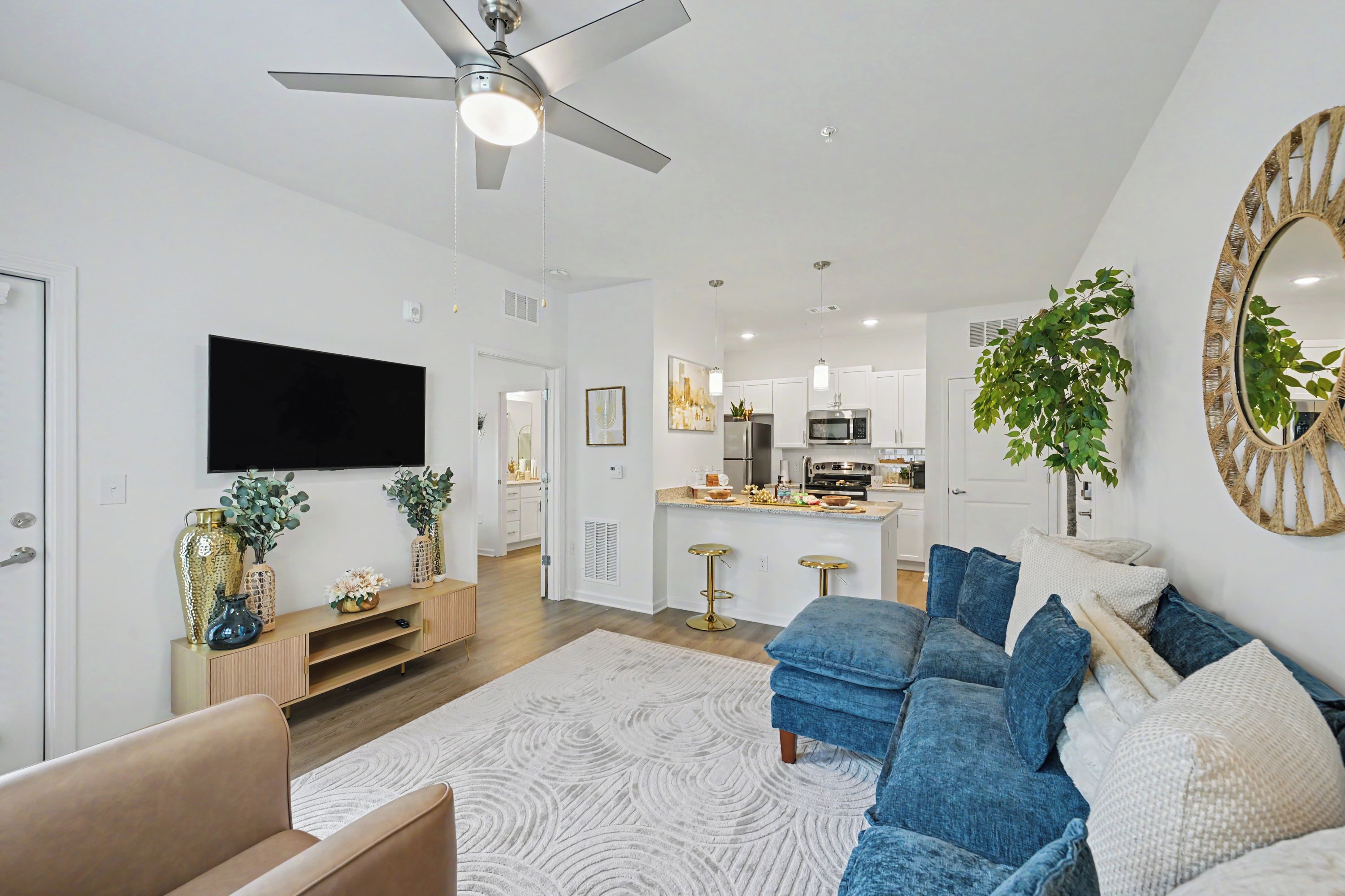 Un salon moderne avec un canapé bleu, un téléviseur à écran plat et un ventilateur de plafond.