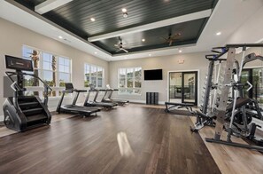 A gym with treadmills, a weight machine, and a television screen. - Grand Boho Suite / Queen Bed-Pool-Gym Near Airpot (Jacksonville)