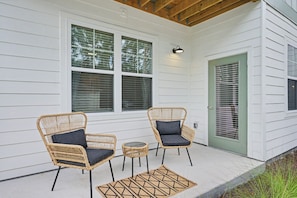 A porch with two wicker chairs and a small table, a green door, and a window with blinds. - Grand Boho Suite / Queen Bed-Pool-Gym Near Airpot (Jacksonville)