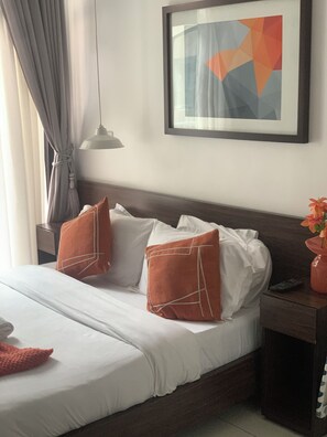 A hotel room with a bed, pillows, a nightstand, a lamp, and a framed picture on the wall. - Charming apartment in beautiful Accra with cool AC and gym access (Accra)