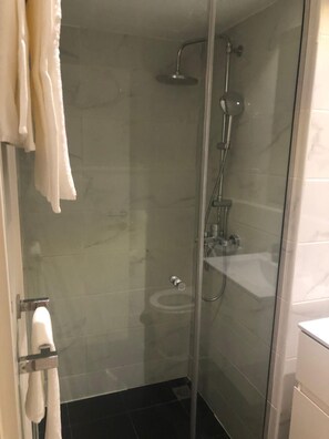 A glass-enclosed shower stall with a handheld showerhead and a wall-mounted faucet. - Charming apartment in beautiful Accra with cool AC and gym access (Accra)