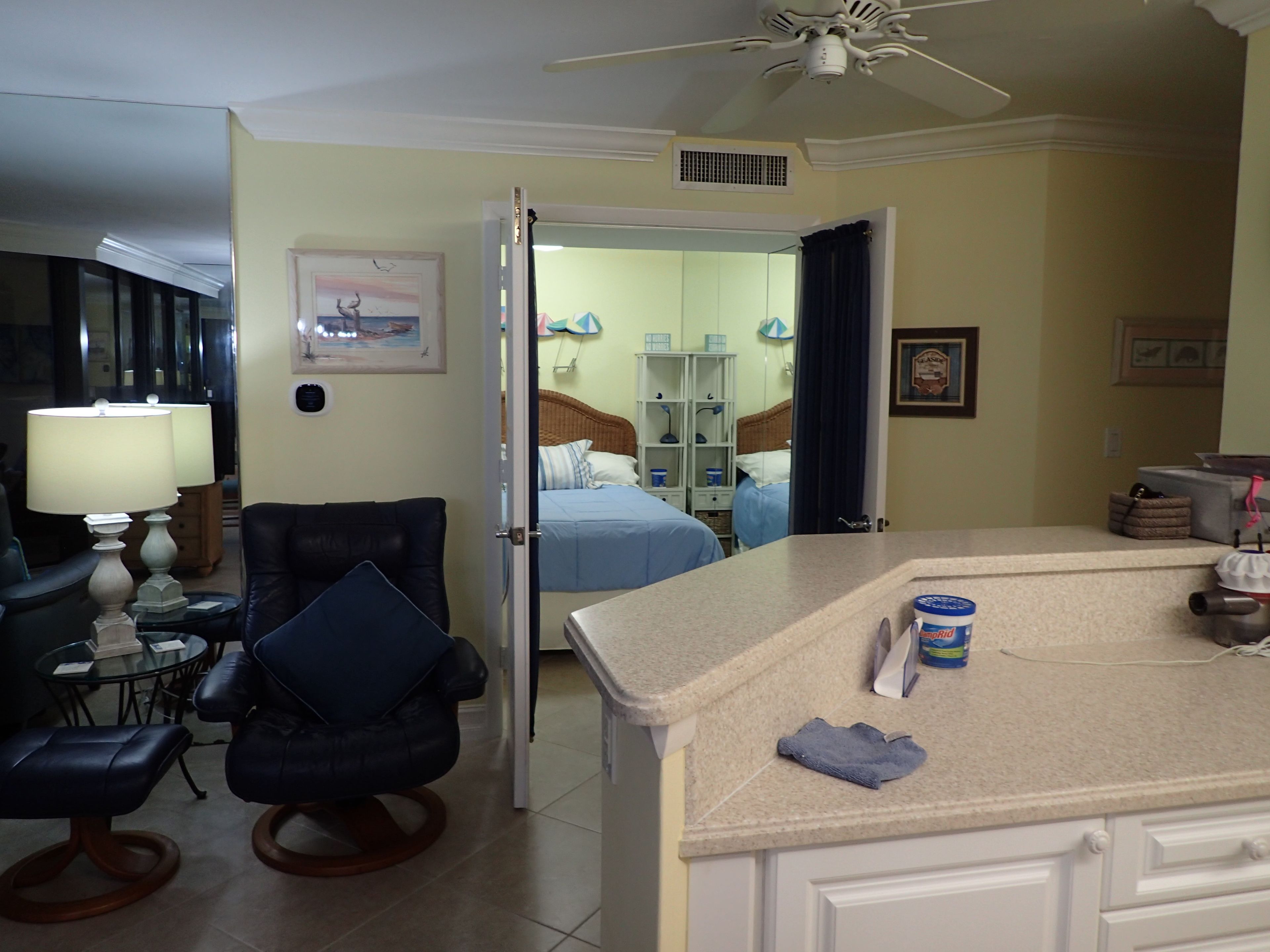 A hotel room with a bed, a desk, a chair, a lamp, and a ceiling fan.
