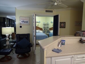 A hotel room with a bed, a desk, a chair, a lamp, and a ceiling fan. - 2-bedroom beachfront condo in Marco Island with fitness room,pool,picketball (Marco Island)