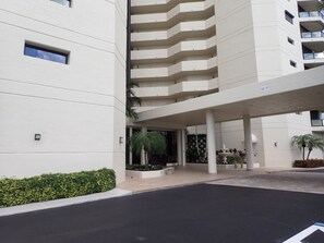 A modern building with a covered entrance, a parking area, and a landscaped garden. - 2-bedroom beachfront condo in Marco Island with fitness room,pool,picketball (Marco Island)